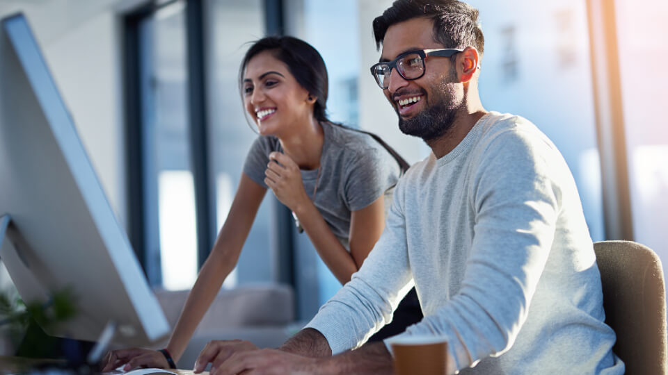 Two happy office workers looking at a computer screen